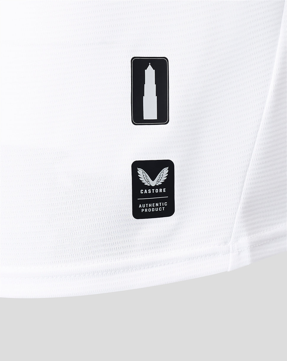 Close-up of white shirt fabric showing two black badges a tower icon and Castore authentic product