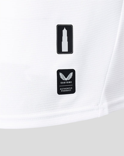 Close-up of white shirt fabric showing two black badges a tower icon and Castore authentic product