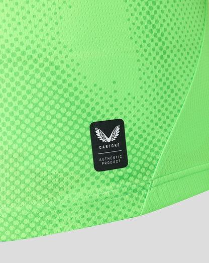 Close-up of neon green fabric with a Castore authentic product badge on the chest area.