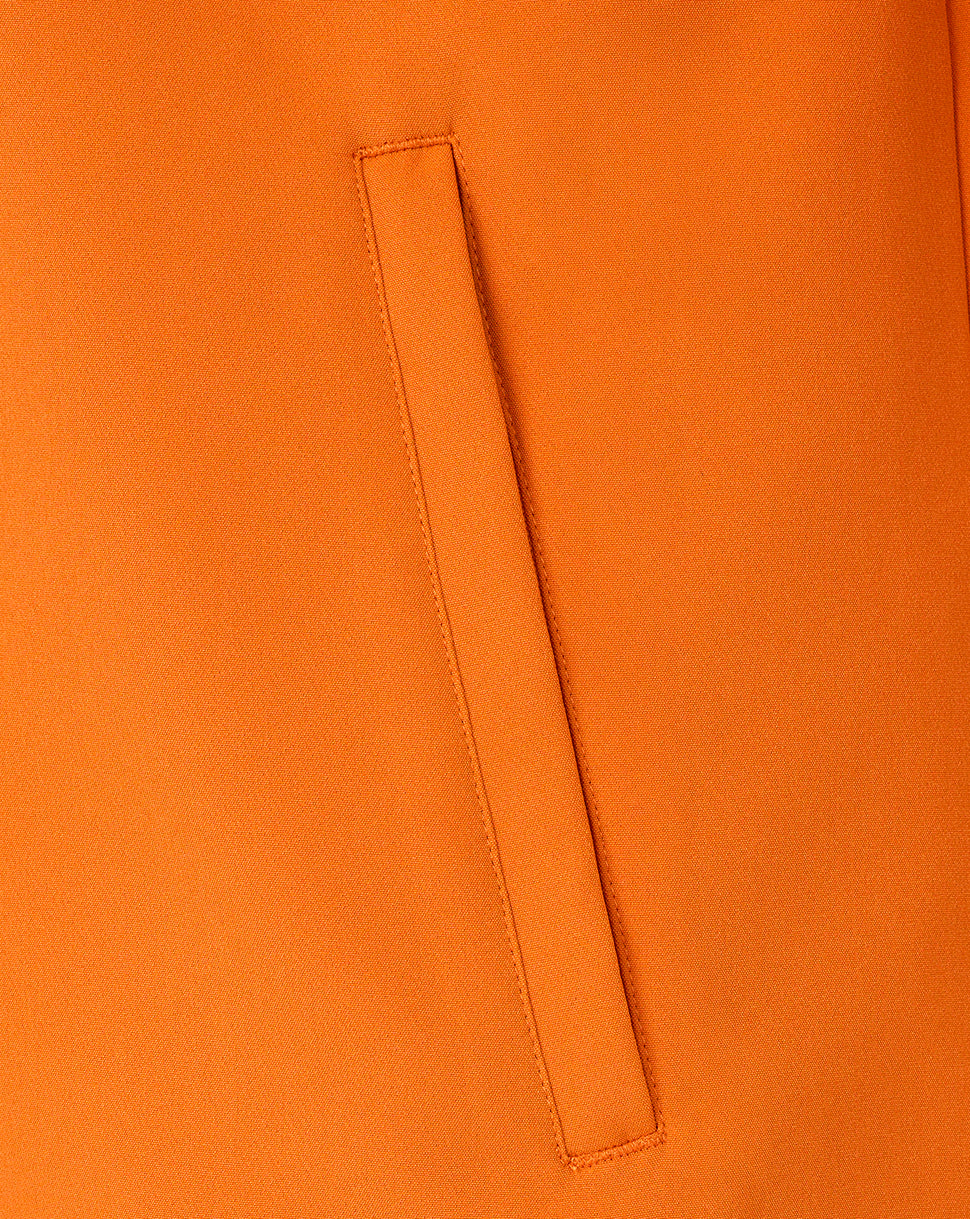 Close-up of a bright orange fabric surface with a vertical stitched welt pocket detail.