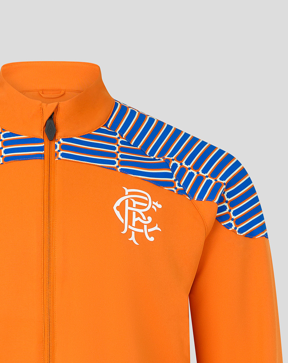 Close-up of an orange zip-up jacket with blue and white striped shoulder panels and a white embroidered crest on the chest, shown against a light gray background.