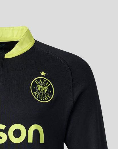 Close-up of a Bath Rugby athletic top in black with a bright yellow collar and yellow logo details, including the Bath Rugby crest and partial sponsor text.