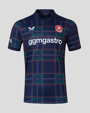 A short-sleeve football jersey by Castore, featuring a navy blue base with a green and red tartan plaid pattern. The jersey has a white 'gmgastro' sponsor logo across the chest, a red and white club crest on the right chest, and a white Castore logo on the left chest, set against a solid light gray background.