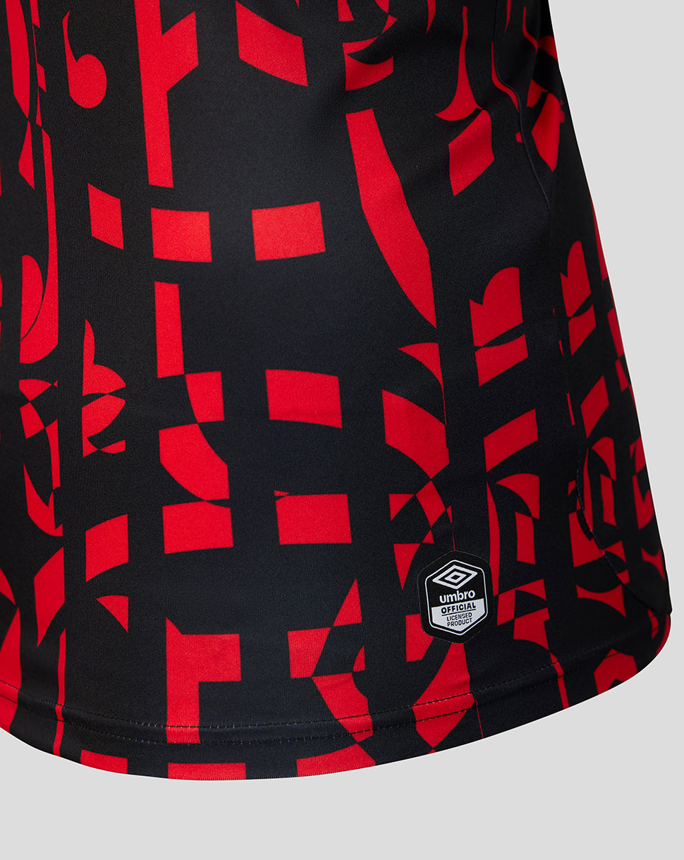 Close-up of a black athletic jersey with a bold red geometric pattern and a small white Umbro logo patch near the lower hem.