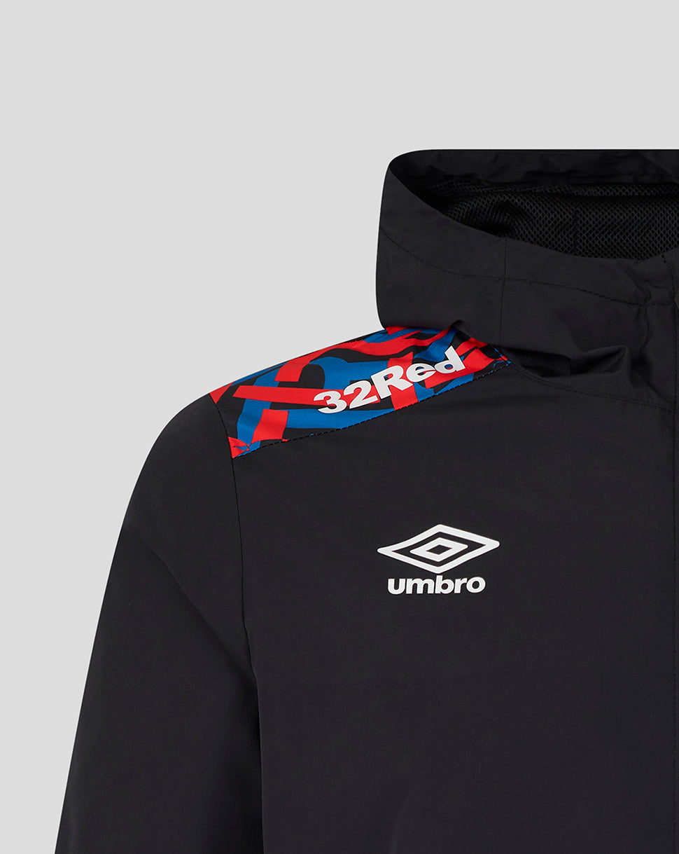 Close-up of a black Umbro athletic jacket with a red and blue patterned shoulder yoke and white Umbro logo on the chest.
