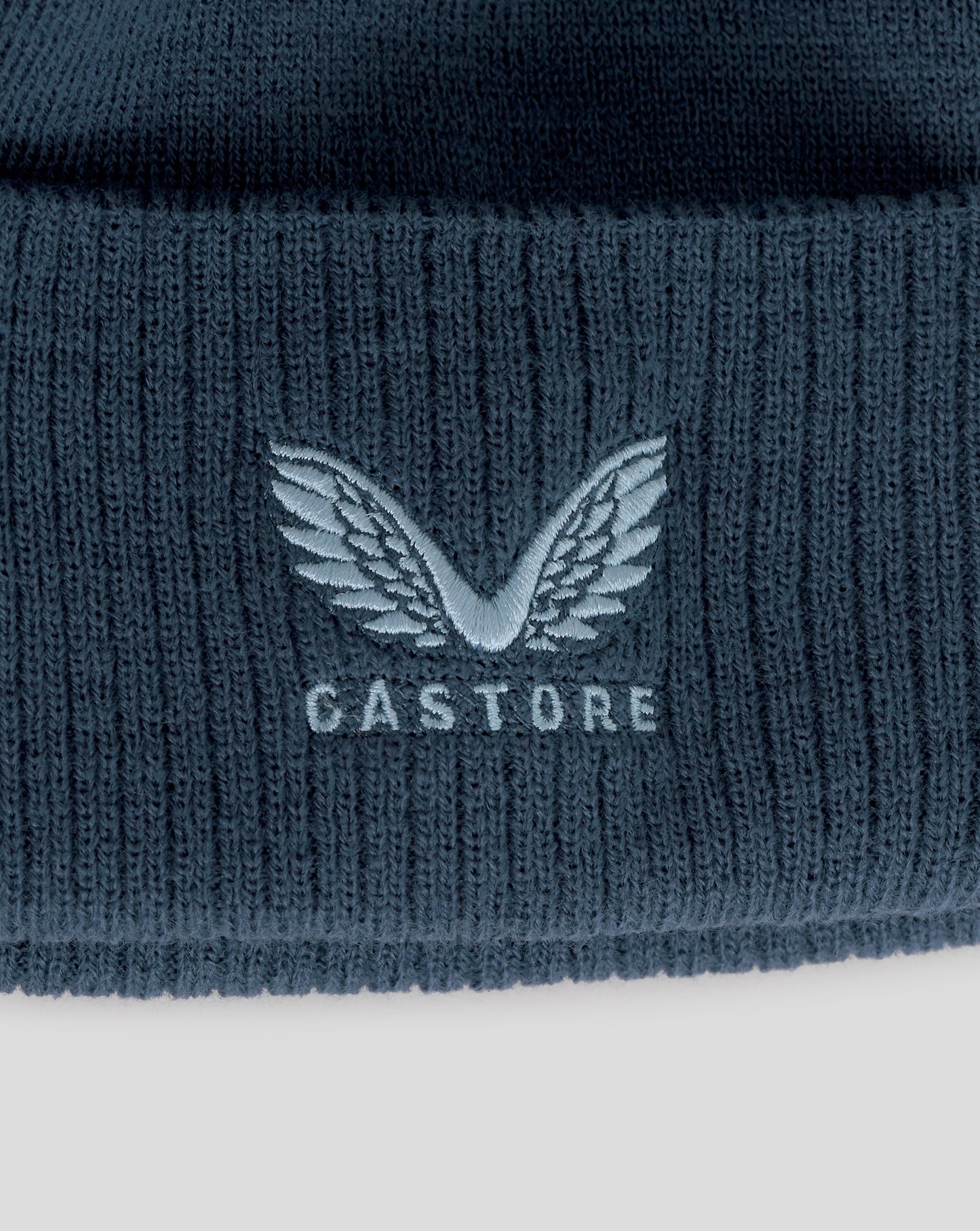 Navy blue knit beanie with Castore logo on a white background