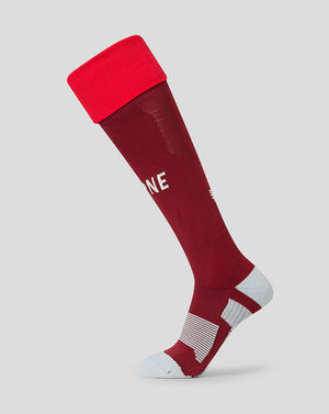 A single athletic knee-high sock shown on a ghost mannequin against a light gray background. The sock is primarily deep burgundy with a bright red cuff, white text on the side, and white striped cushioning on the sole.