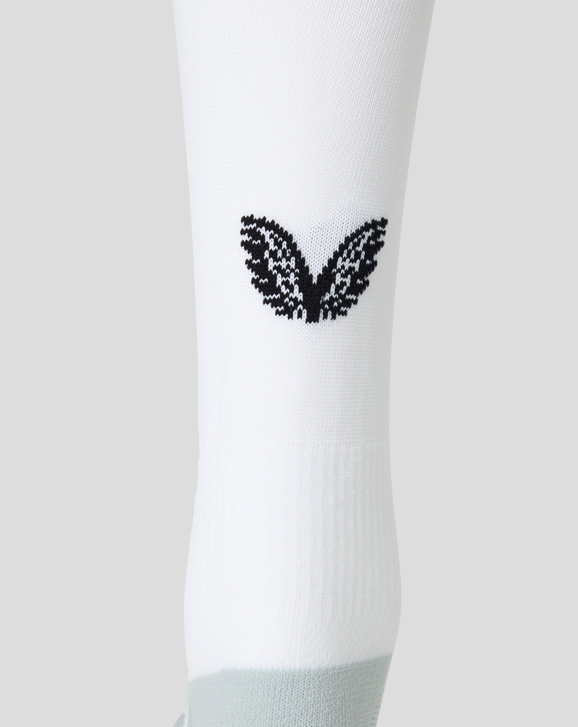A close-up of a white athletic sock featuring a black knit wing design on the side and a light gray ribbed toe section, set against a solid light gray background.
