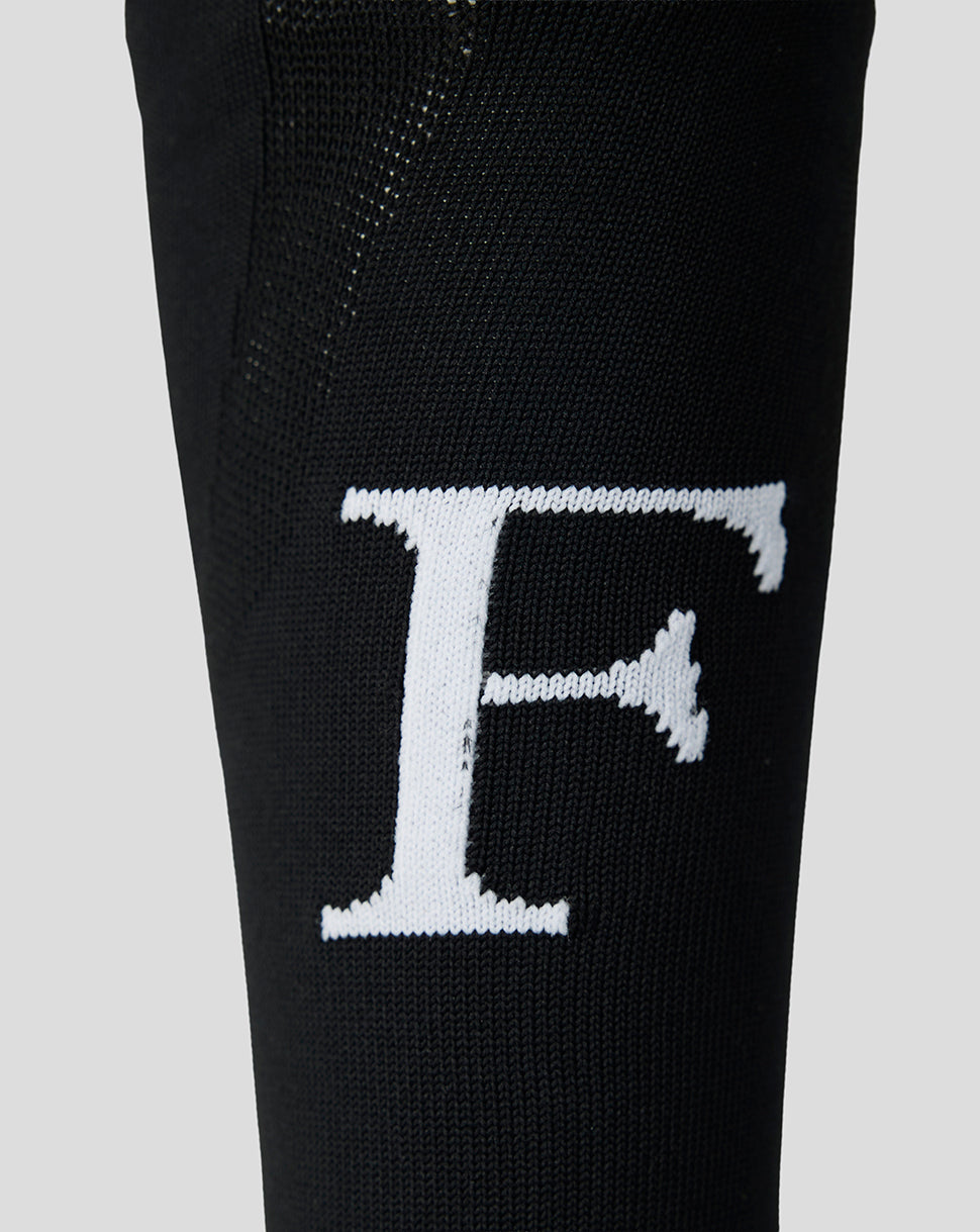 Close-up of white Feyenoord F logo on black sock leg.