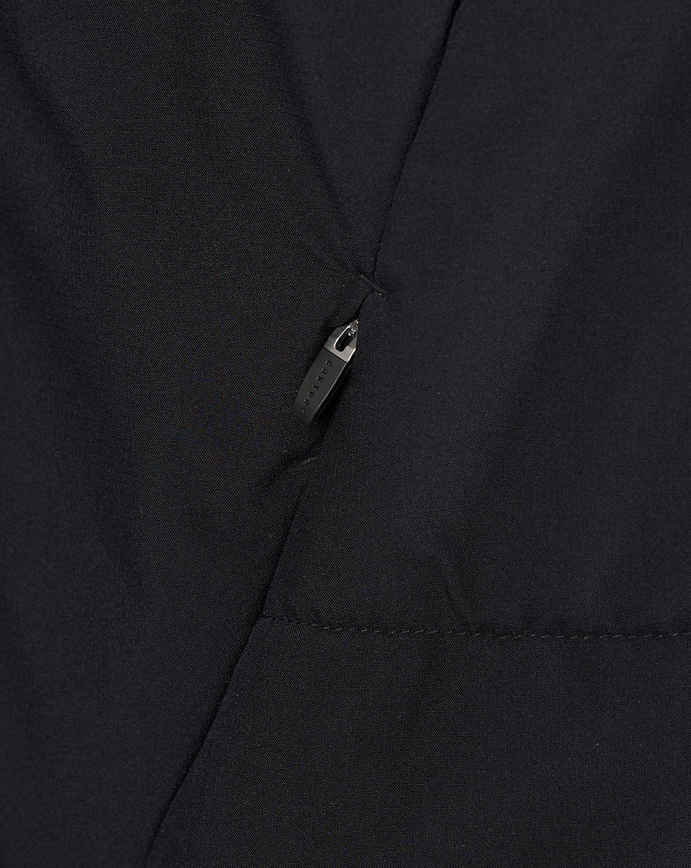 Close-up of a black fabric garment with a diagonal seam and a small black zipper pull.