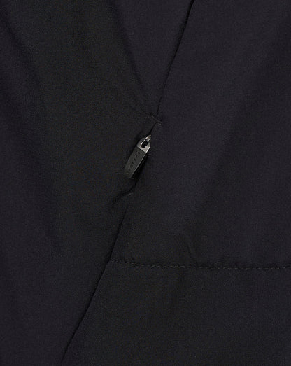 Close-up of a black fabric garment with a diagonal seam and a small black zipper pull.