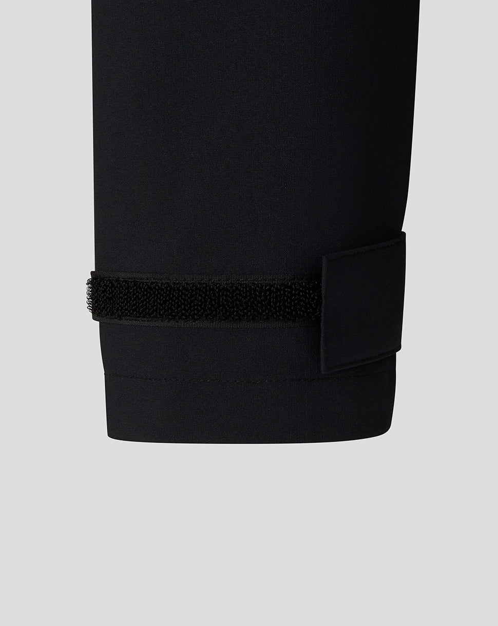 Close-up of a black pants cuff with a elastic band on a light gray background