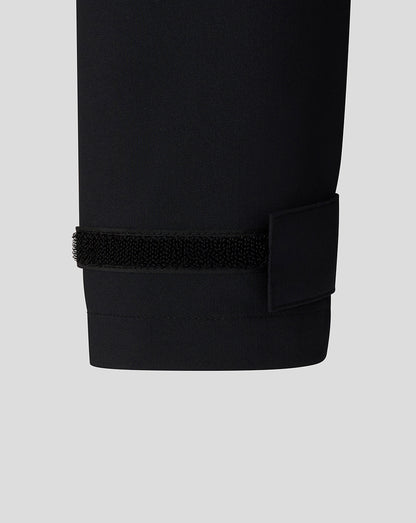 Close-up of a black pants cuff with a elastic band on a light gray background