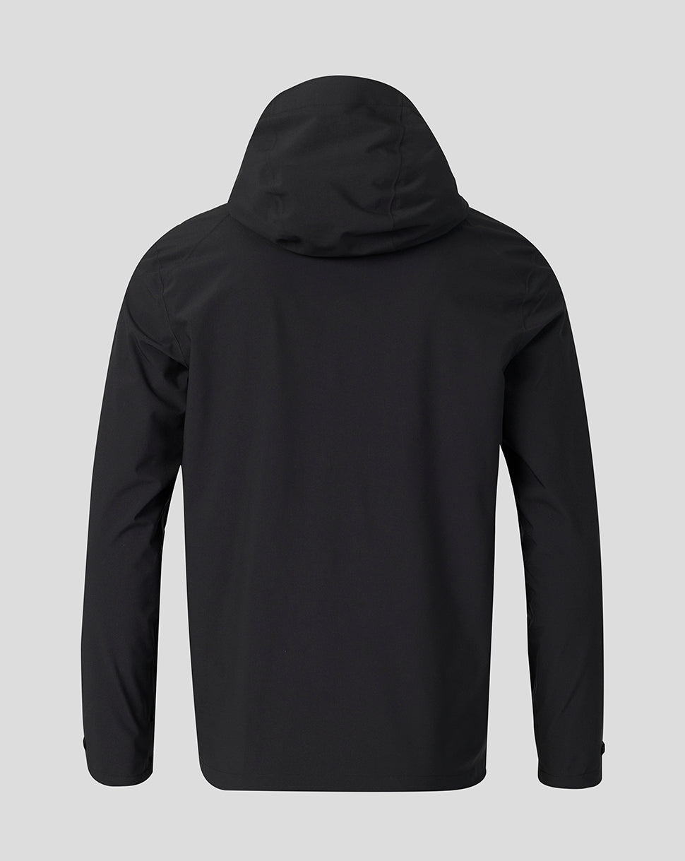 A black hooded jacket shown from the back, featuring long sleeves and a smooth matte finish, set against a solid light gray background.