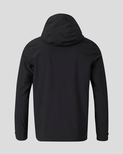 A black hooded jacket shown from the back, featuring long sleeves and a smooth matte finish, set against a solid light gray background.