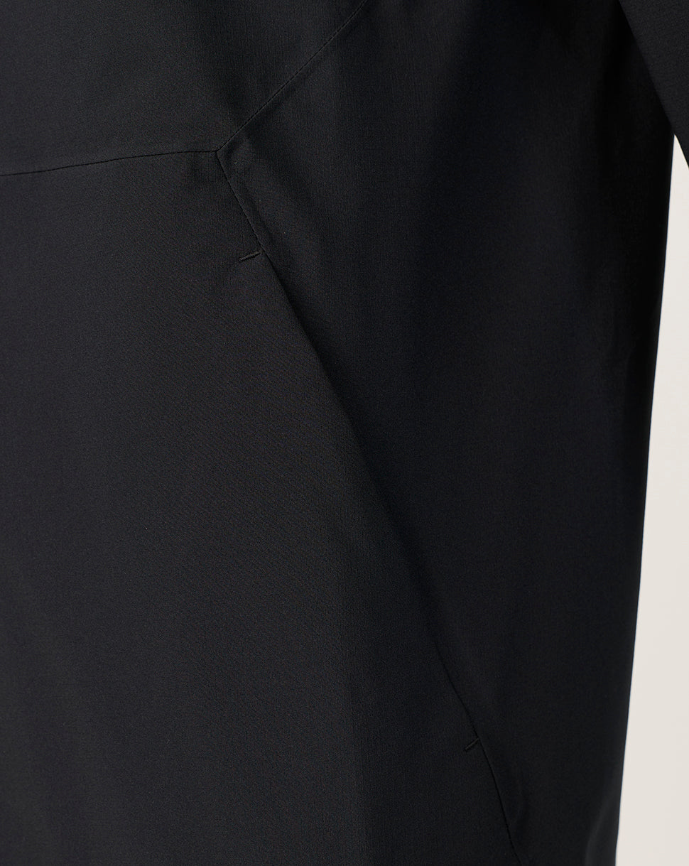 Close-up of a black garment showing a seam and fabric texture against a light neutral background.