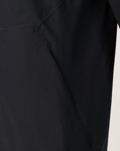 Close-up of a black garment showing a seam and fabric texture against a light neutral background.