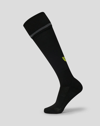 A single black knee-high athletic sock with a small yellow logo on the side and a gray ribbed band at the top cuff, shown against a solid light gray background.