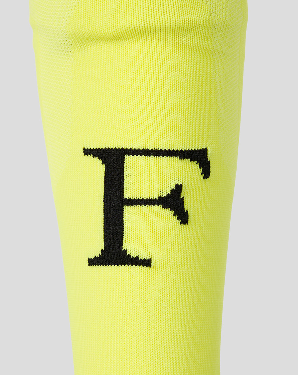 Close-up of neon yellow Feyenoord Junior Away goalkeeper sock showing a large black Feyenoord F on the shin