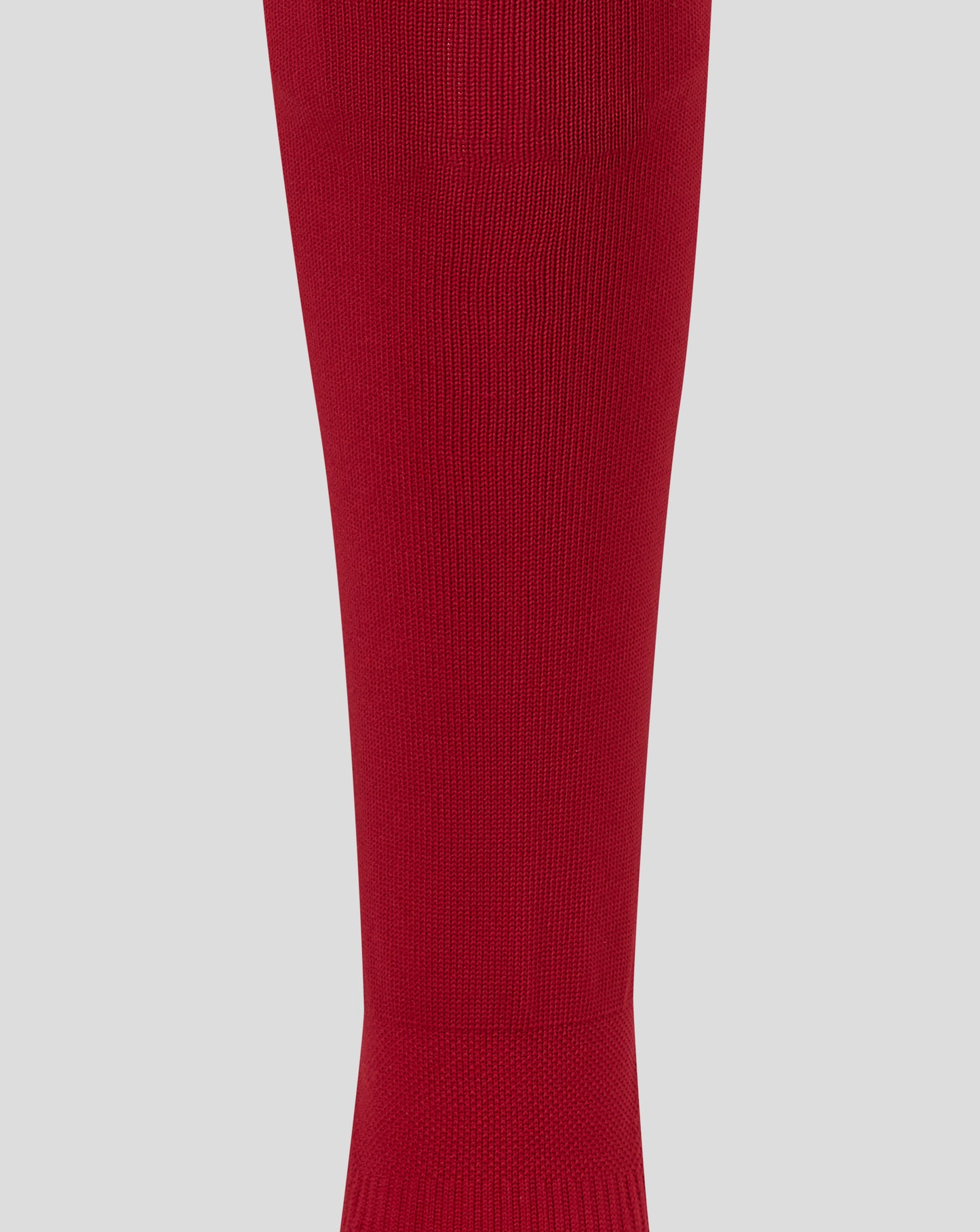A close-up of a ribbed knit red sock or leg sleeve shown vertically against a light gray background.