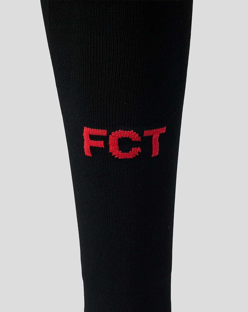 Close up of black FC Twente away sock displaying red embroidered FC T letters