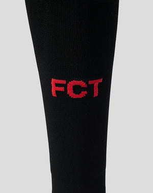 Close up of black FC Twente away sock displaying red embroidered FC T letters