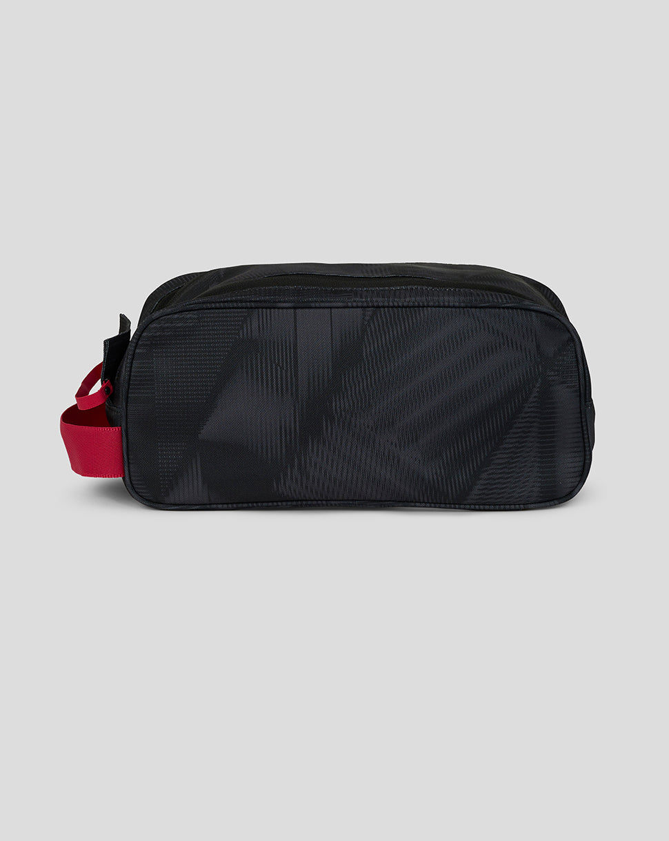 Black toiletry bag with a red strap on a light gray background