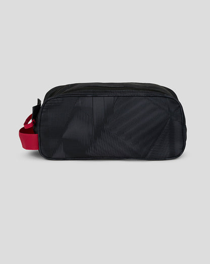 Black toiletry bag with a red strap on a light gray background