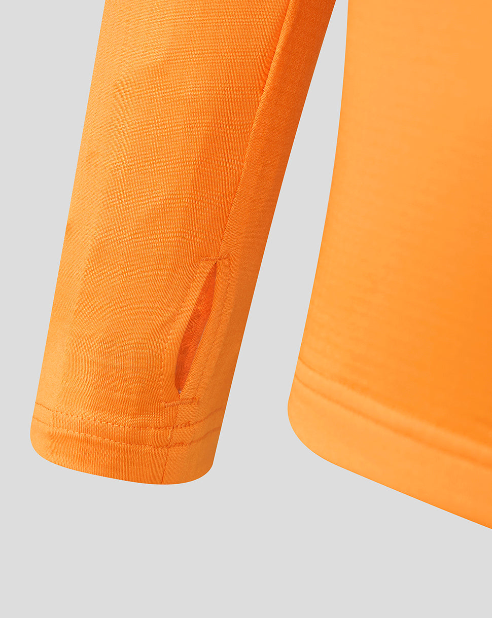 Close up of orange training midlayer sleeve with a vent slit and textured knit.