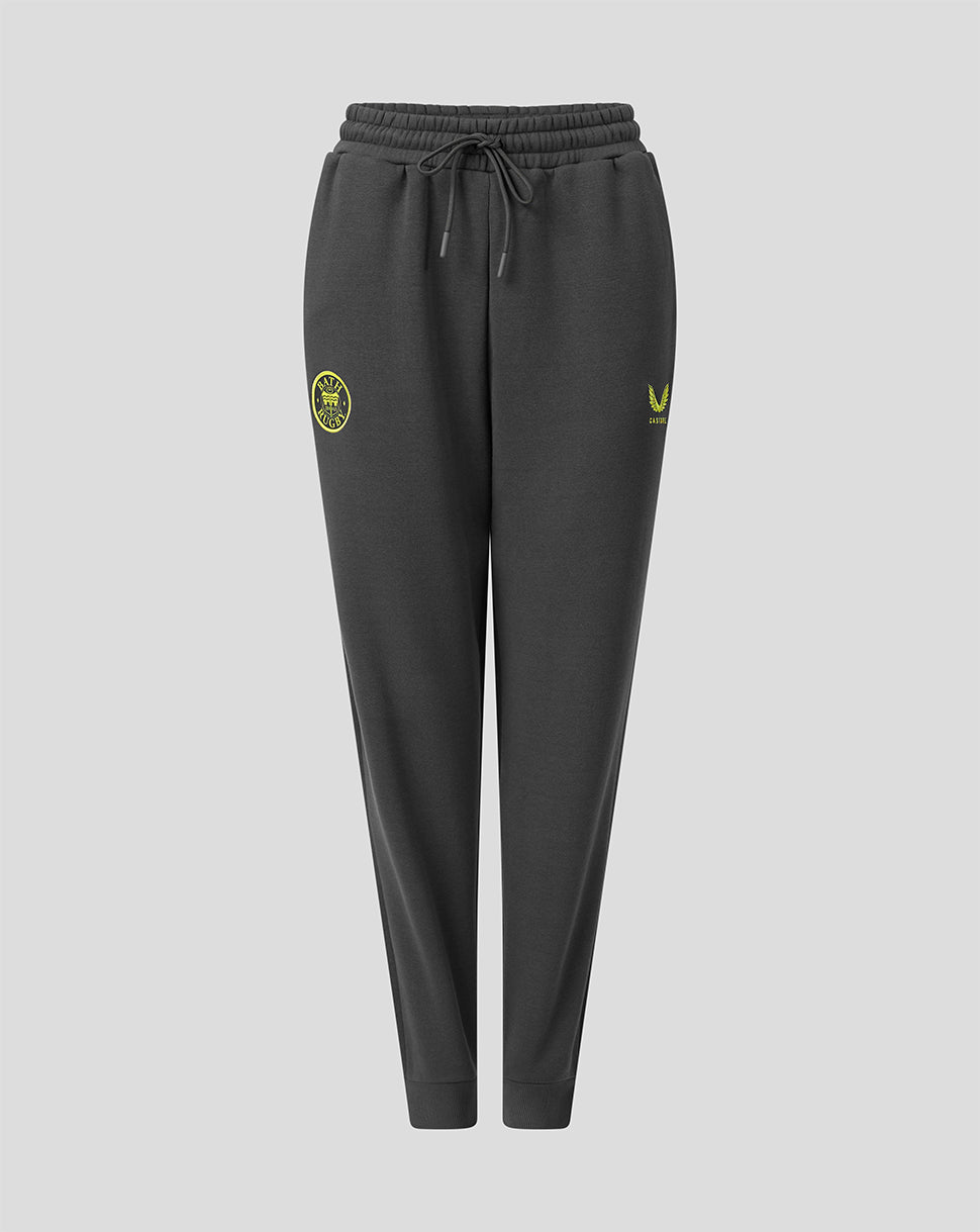 Dark gray jogger sweatpants with a drawstring waist, featuring a yellow-green circular crest on the left thigh and a matching logo on the right thigh, shown against a light gray background.