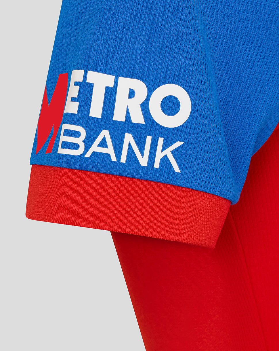 Close-up of a blue and red sweater with 'Metro Bank' logo on a light gray background
