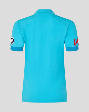 Blue polo shirt with brand logos on sleeves against a gray background