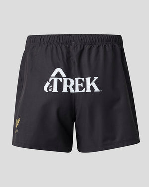 Black athletic shorts with a white 'TREK' logo on the front and a small gold fern logo on the lower left leg, shown against a light gray background.