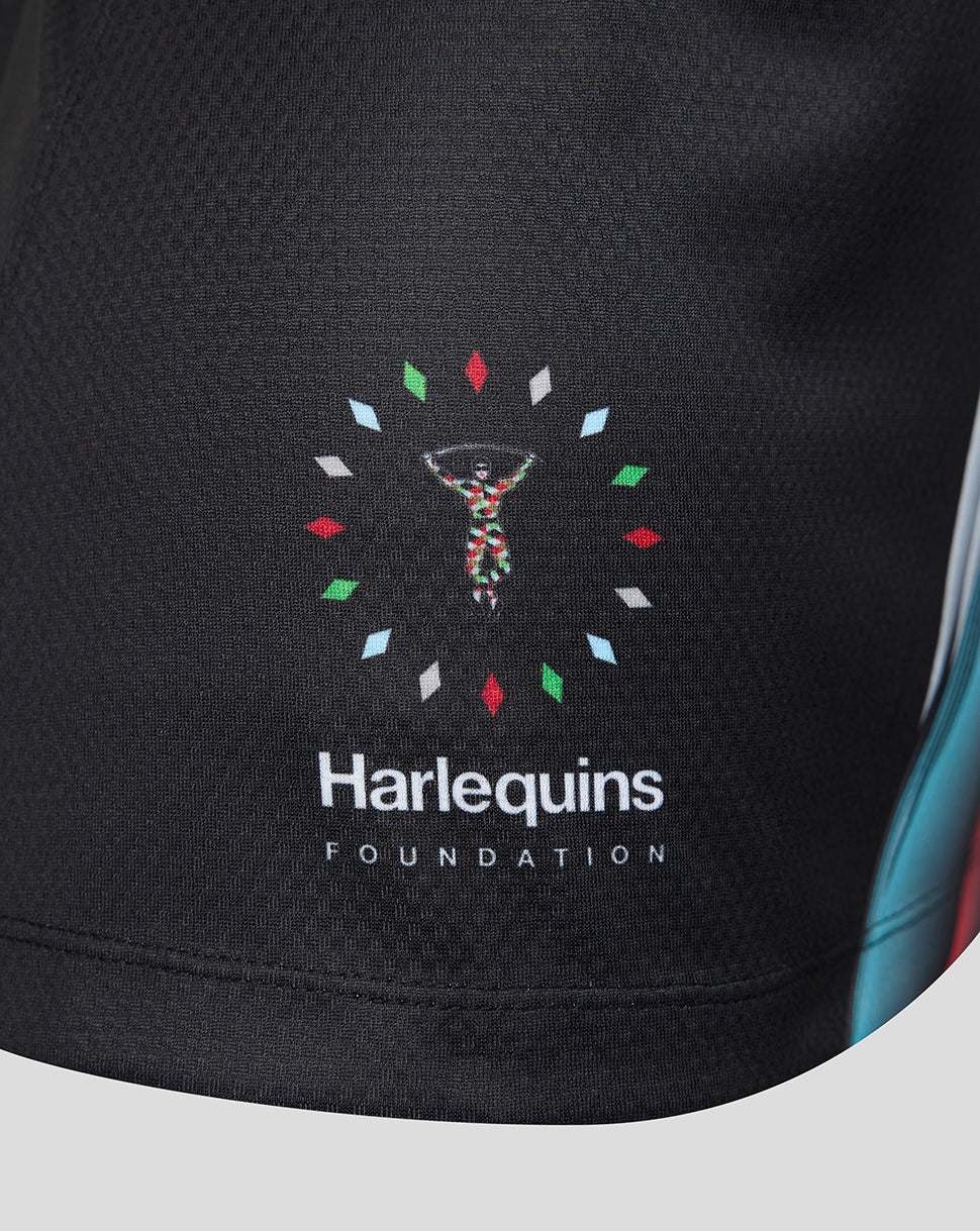 Close-up of a black athletic jersey with the 'Harlequins Foundation' logo printed on the front. The logo features a central figure in a colorful pattern surrounded by small multicolored diamond shapes.