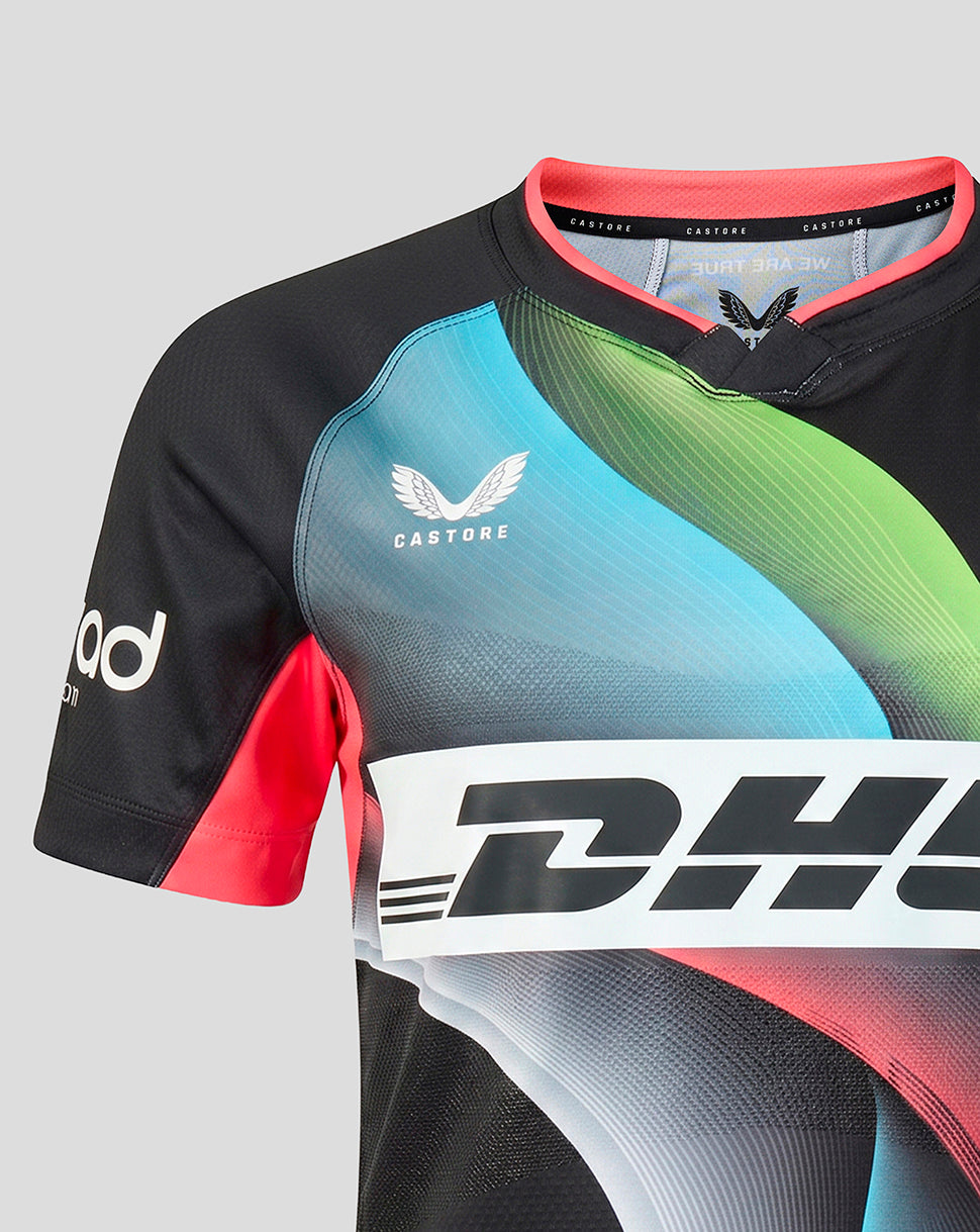 A close-up of a short-sleeve rugby jersey with a black base and a vibrant multicolor graphic design featuring shades of blue, green, and pink. The jersey has a white Castore logo on the chest and a large white DHL logo across the front.