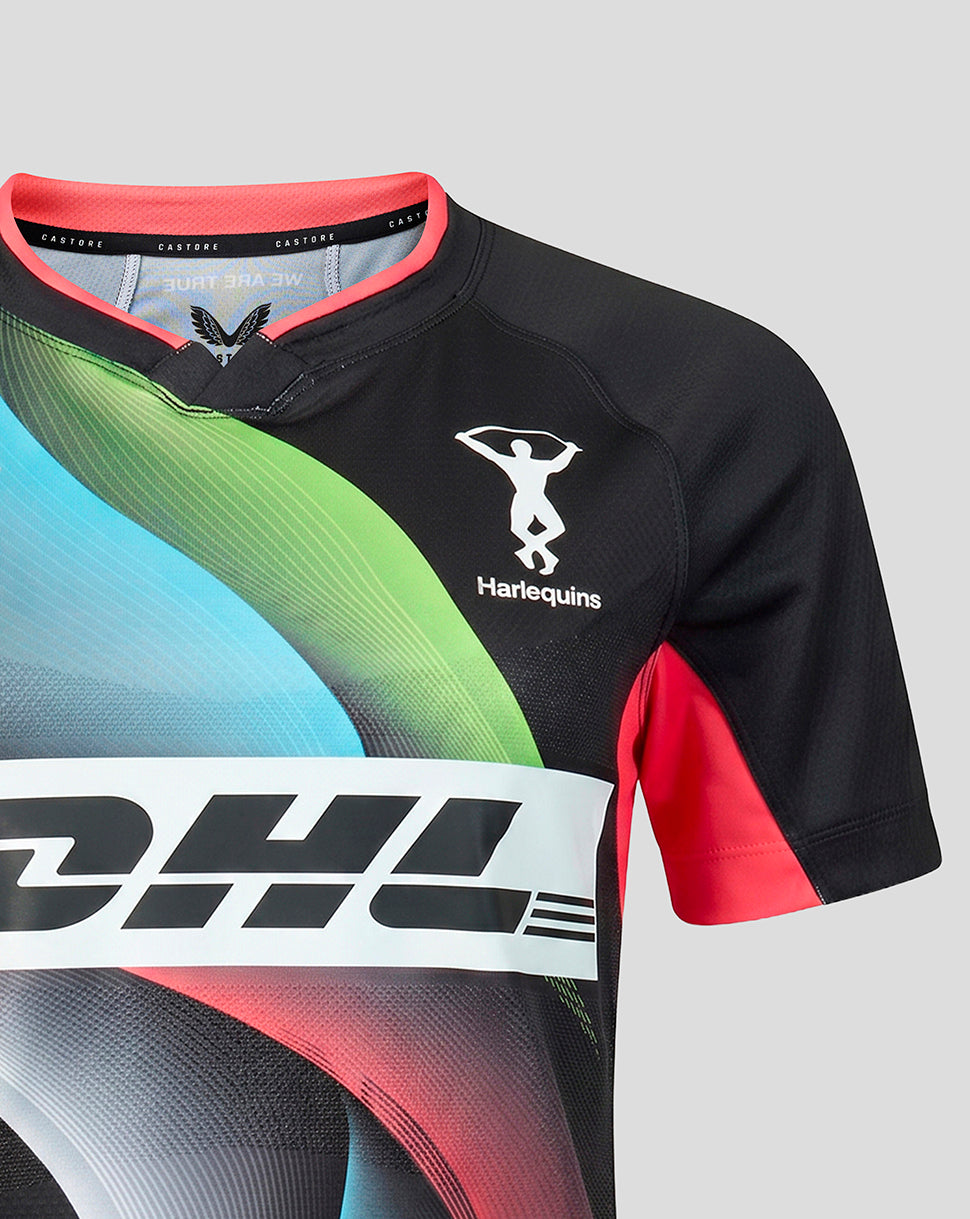 A close-up of a short-sleeve rugby jersey in black with vibrant abstract wave graphics in green, blue, and pink, featuring a white Harlequins logo and a large white sponsor bar across the front.