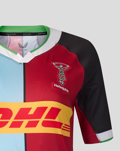Close-up of a short-sleeve sports jersey with a split color design: light blue on the left, red on the right, and black on the sleeves. The jersey has a green collar trim, a central vertical stripe, a multicolor Harlequin logo with 'Harlequin' text on the chest, and a large yellow DHL logo across the front.
