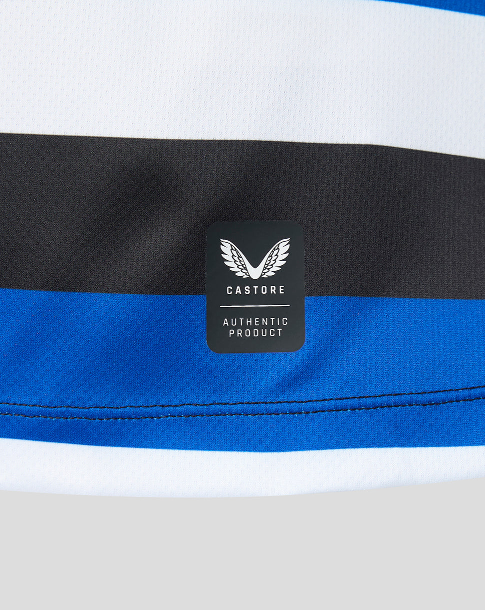 Close-up of a striped athletic garment showing white, black, and royal blue horizontal bands, with a black Castore brand patch on the fabric.