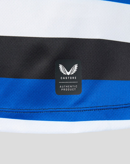Close-up of a striped athletic garment showing white, black, and royal blue horizontal bands, with a black Castore brand patch on the fabric.