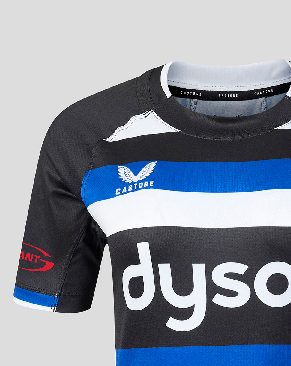 Close-up of a rugby jersey in black, white, and blue, featuring the Castore brand logo and a partial Dyson sponsor logo on a light gray background.