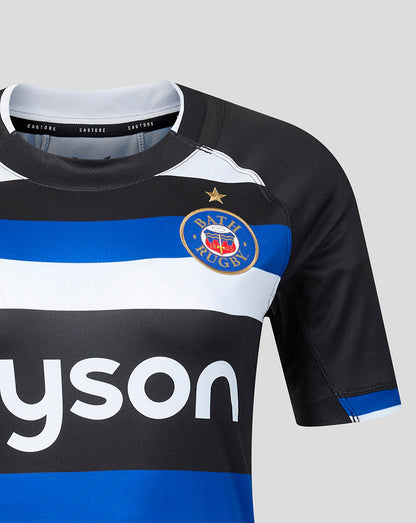 A close-up of a rugby jersey with black, white, and blue horizontal stripes, featuring the bath rugbylogo on the chest and a visible Castore brand label inside the collar.