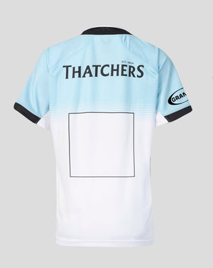 Back view of a light blue and white short-sleeve sports jersey with black trim, featuring 'THATCHERS' printed across the upper back and a blank rectangular patch on the lower back.