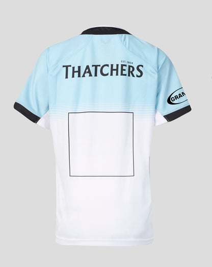 Back view of a light blue and white short-sleeve sports jersey with black trim, featuring 'THATCHERS' printed across the upper back and a blank rectangular patch on the lower back.