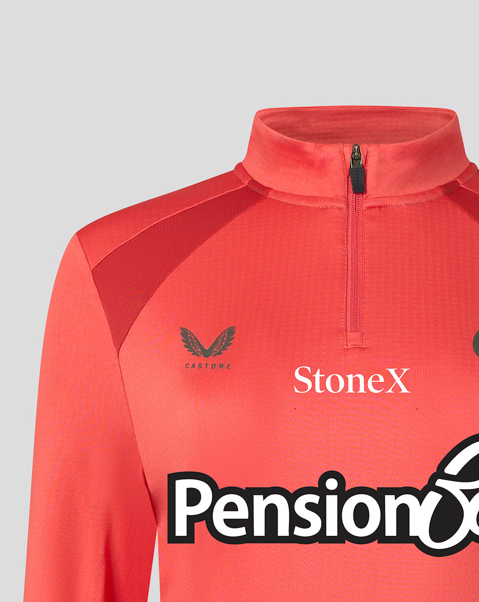 A close-up of a coral red athletic quarter-zip jacket with a mock neck collar. The brand 'Castore' is printed in black on the left chest, and 'StoneX' is printed in white on the right chest.