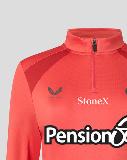 A close-up of a coral red athletic quarter-zip jacket with a mock neck collar. The brand 'Castore' is printed in black on the left chest, and 'StoneX' is printed in white on the right chest.
