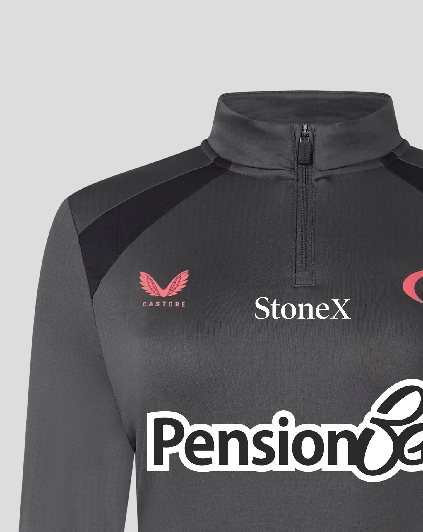 A close-up of a dark gray long-sleeve athletic quarter-zip top with black shoulder panels. The chest features the pink Castore logo, the white StoneX sponsor logo, and a partial white Pension8 logo at the bottom.