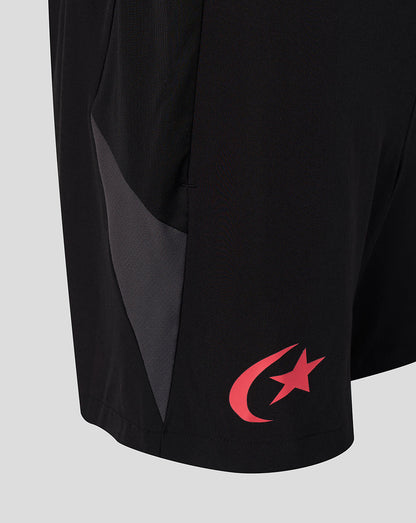 Close-up of black athletic shorts with a dark gray side panel and a red crescent and star logo near the hem, shown on a light gray background.