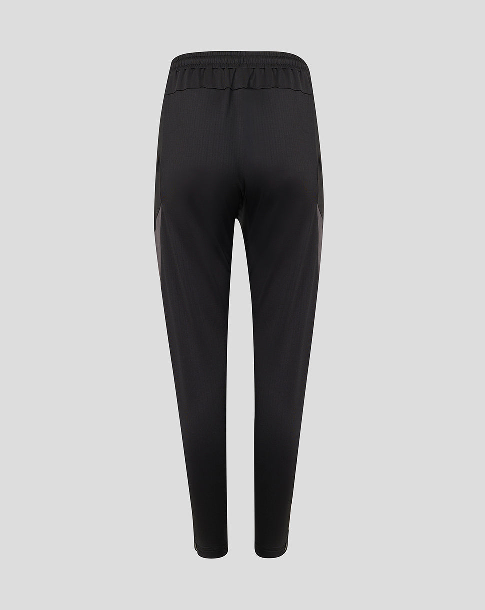 Black athletic pants shown from the back, featuring a gathered elastic waistband and subtle side panel detailing, set against a solid light gray background.