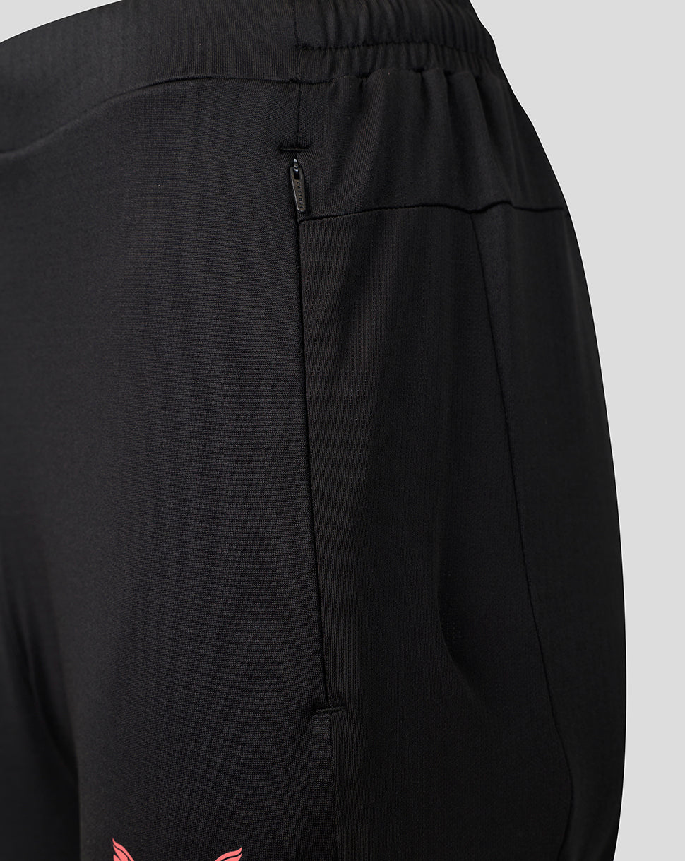 Close-up of black athletic pants showing the side pocket with a zipper, elastic waistband, and a small pink logo near the bottom hem.