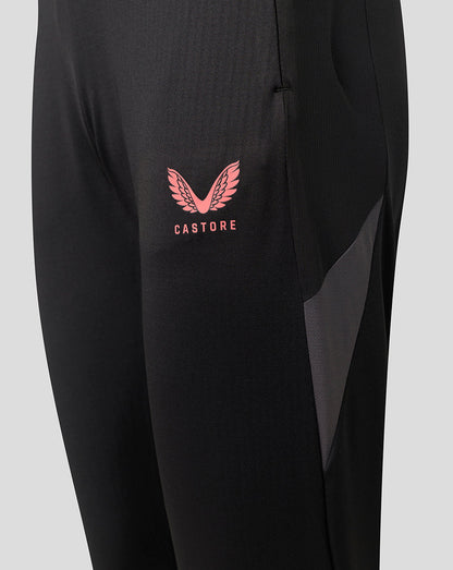 Close-up of black athletic pants featuring a pink Castore wing logo and text on the left thigh, with a dark gray mesh side panel.